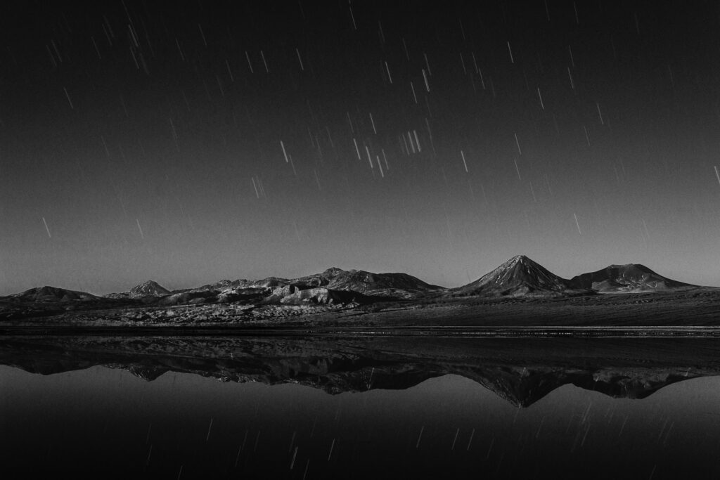 A mountain range with a vast backdrop of stars appearing in the form of a time-lapse.
