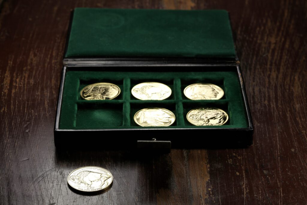 A collection of inherited gold coins displayed in a green velvet-lined box, showcasing the intricate designs on each coin.
