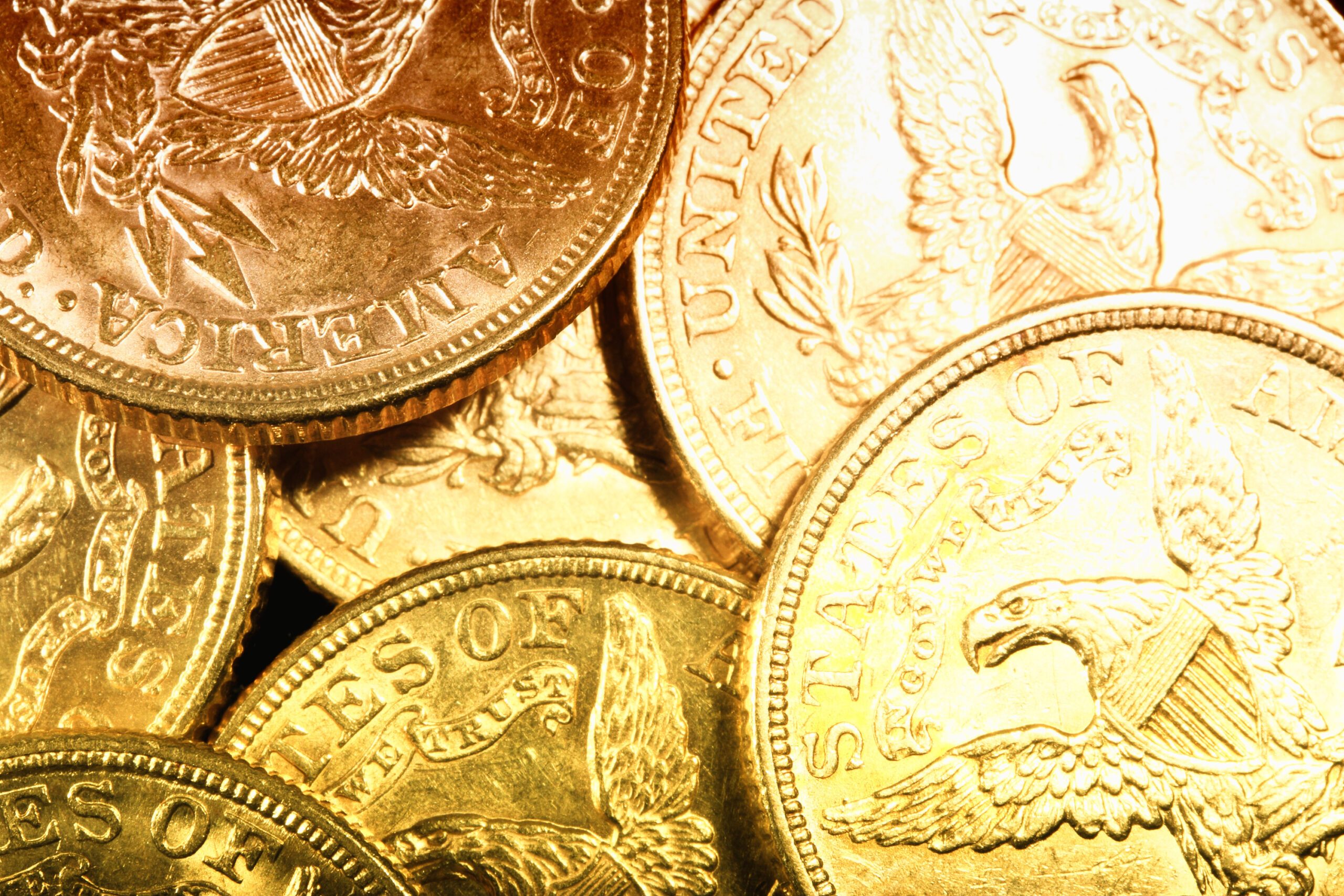 A close-up view of a collection of shiny, inherited gold coins featuring detailed engravings of eagles