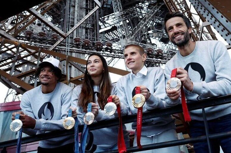 4 Olympic athletes present the 2024 Olympic medals under the Eiffel Tower in Paris, France.