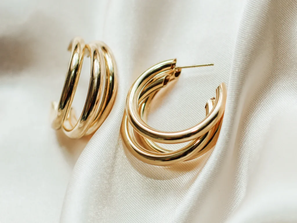 Gold jewelry earrings made of gold on the background of silk.