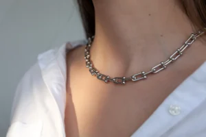Close-up silver chain on  woman with long hair, silver necklace, white shirt neckline