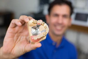 A technician holding a dental crown mold