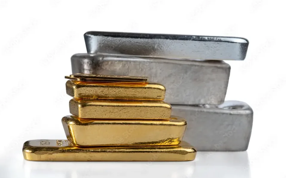 In the foreground, a stack of six gold bullion ingots. In the background, three silver bullion ingots.