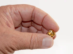 hand holding a gold dental crown on a white background
