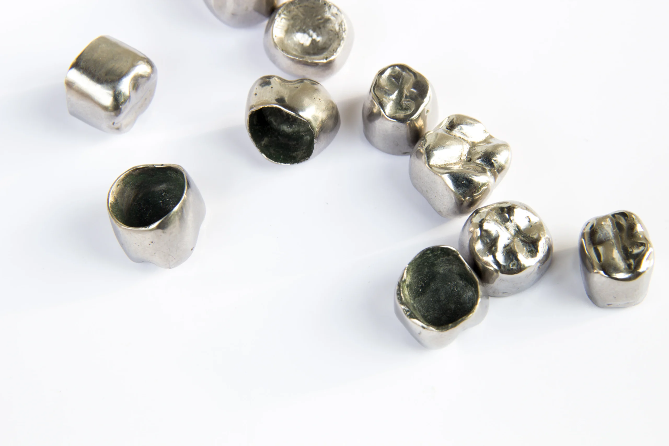 Dental metal tooth crowns on white background.