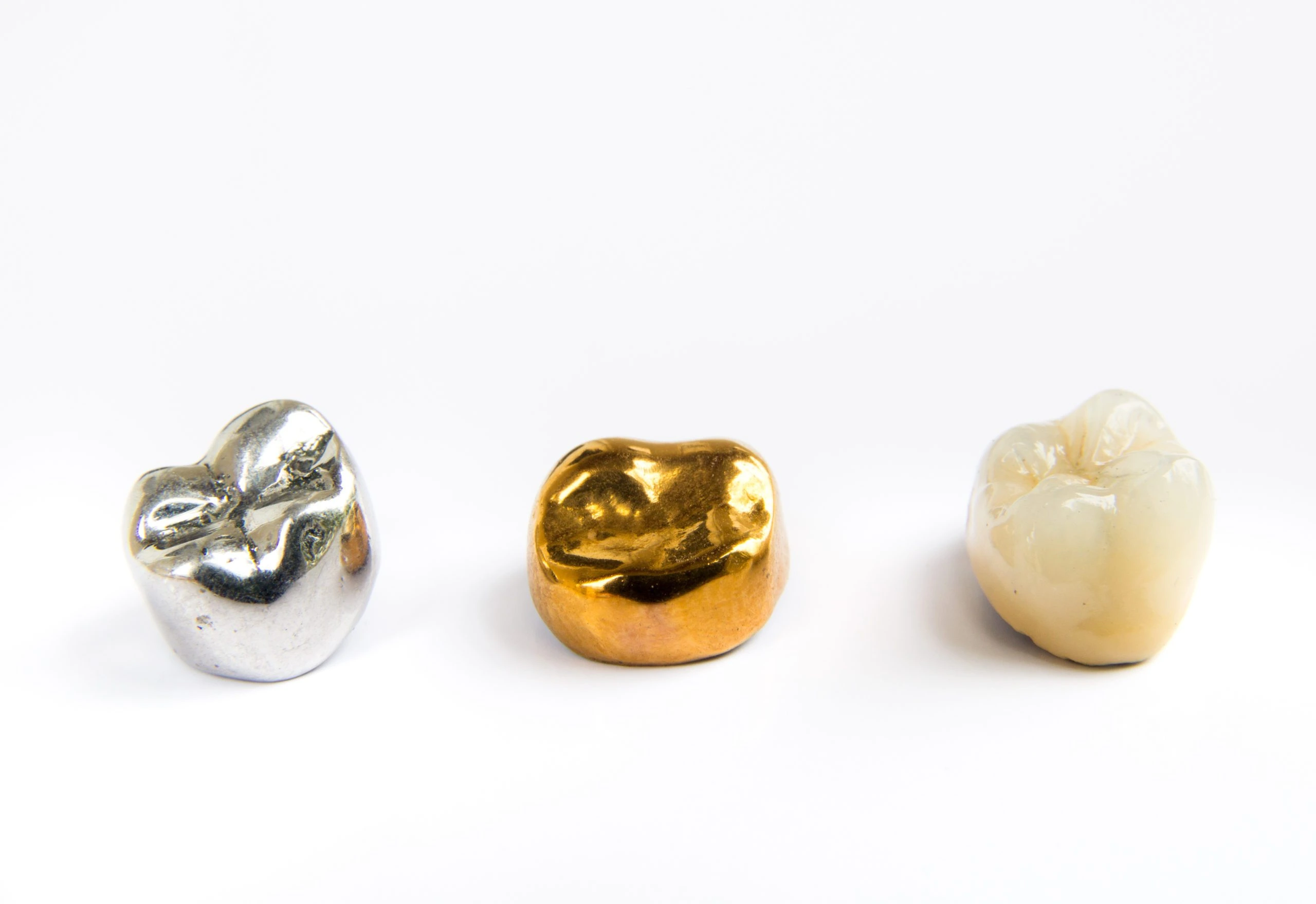 Various precious metal and gold dental scrap crowns on a white background
