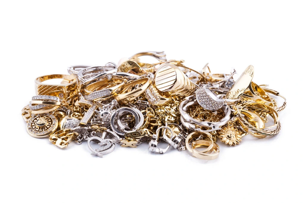 A pile of assorted scrap gold and silver jewelry on a white background
