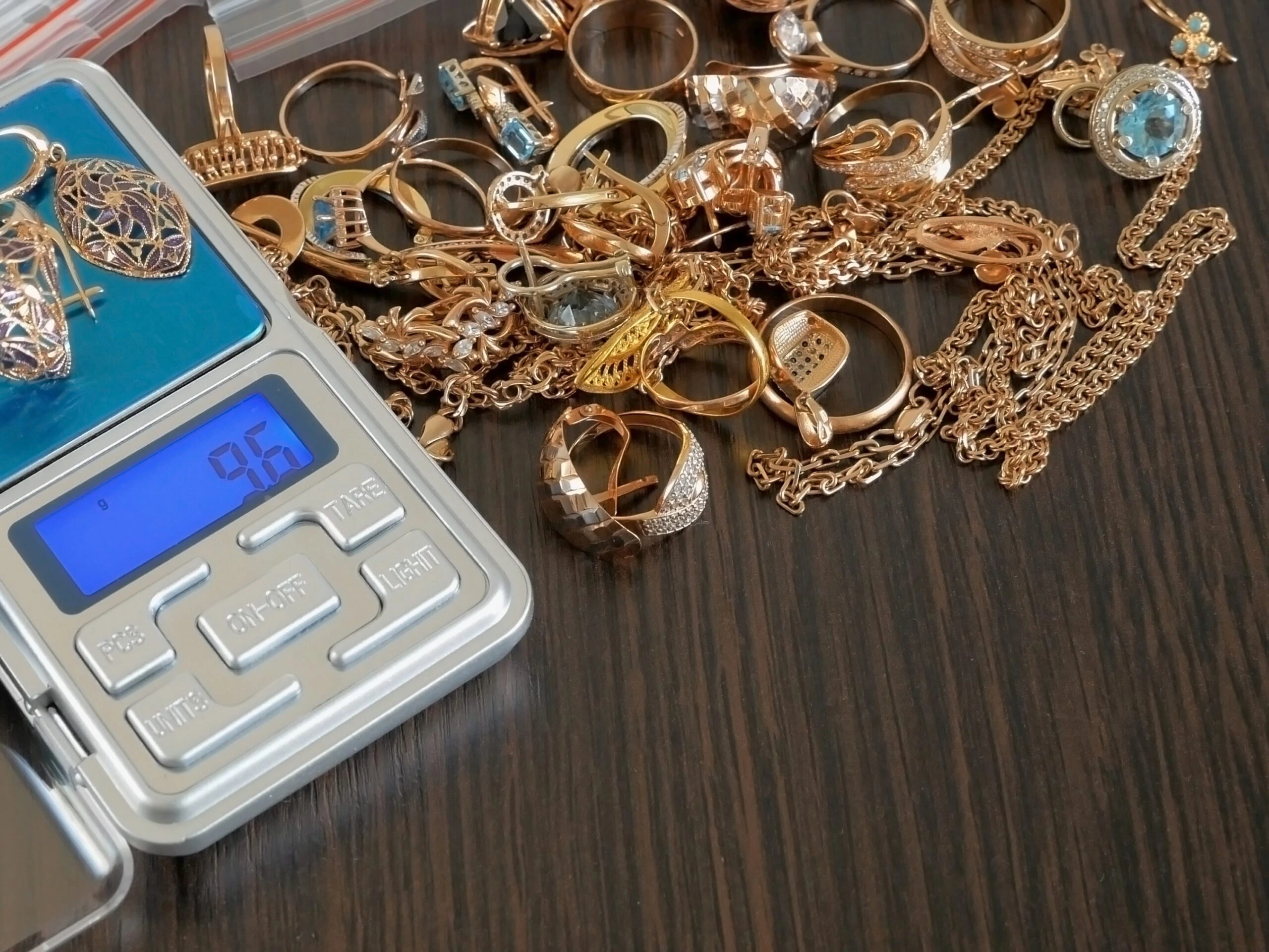 Pawnshop concept, composition with jewelry scales and a lot of gold jewelry on black wooden background