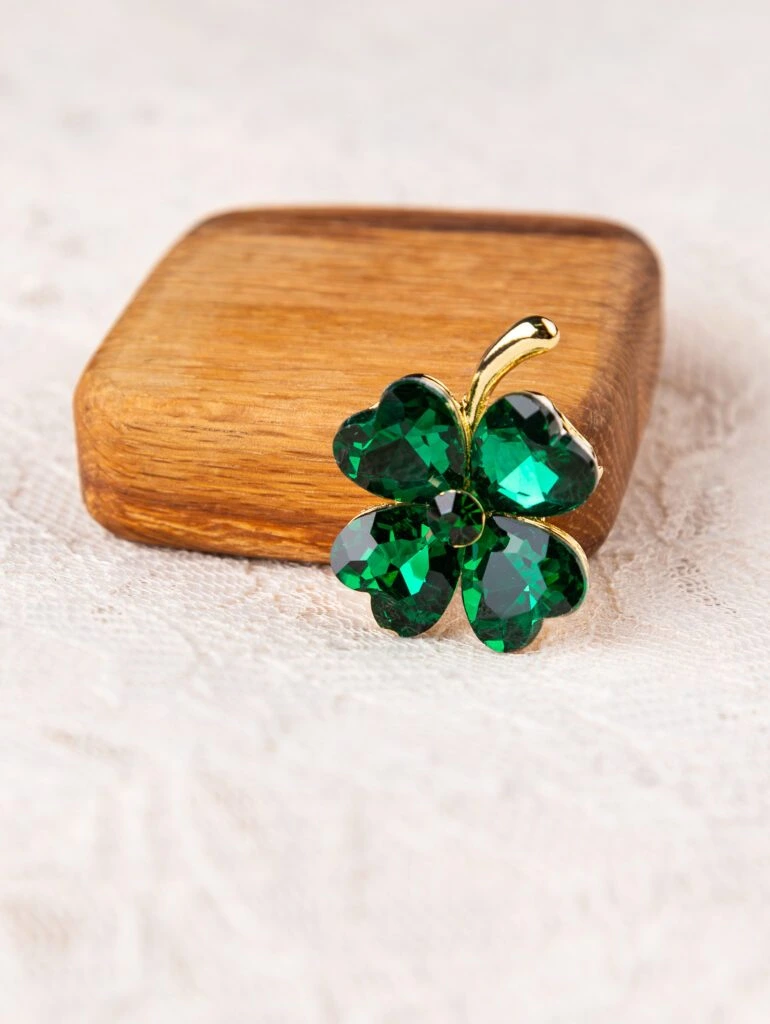 Close up of clover shaped brooch with green stones on white background