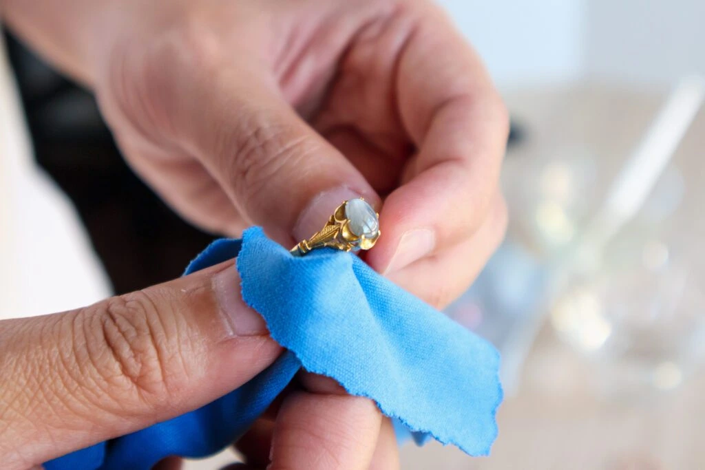Jeweler hand polishing and cleaning gold jewelry ring with micro fiber fabric