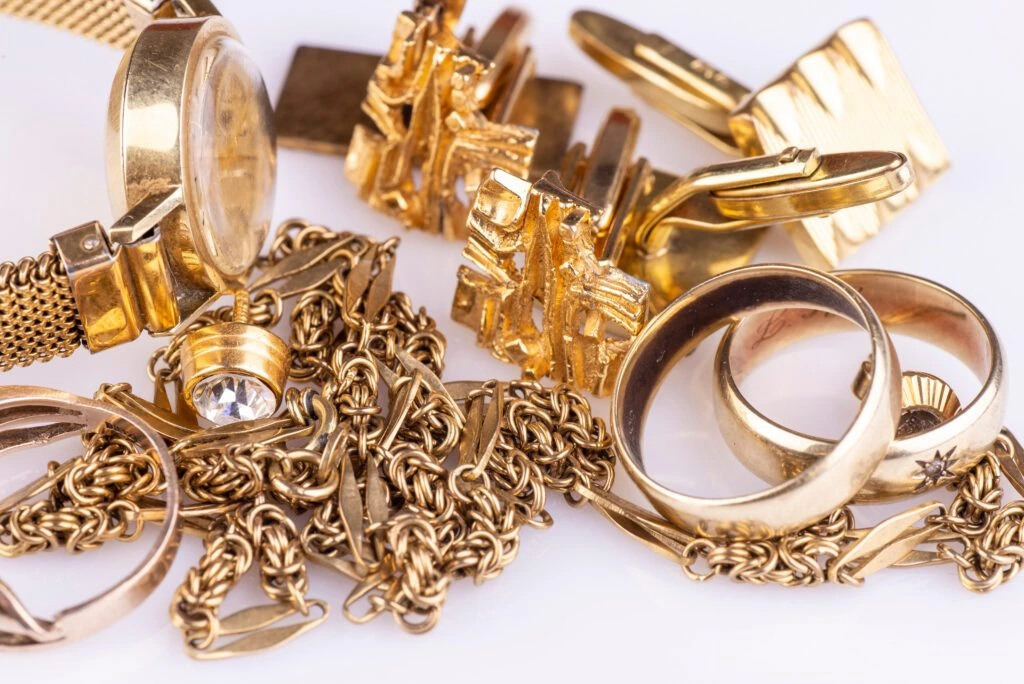 Assorted gold scrap jewelry and accessories, including a wristwatch, cufflinks, a tie clip, chain bracelets, and rings